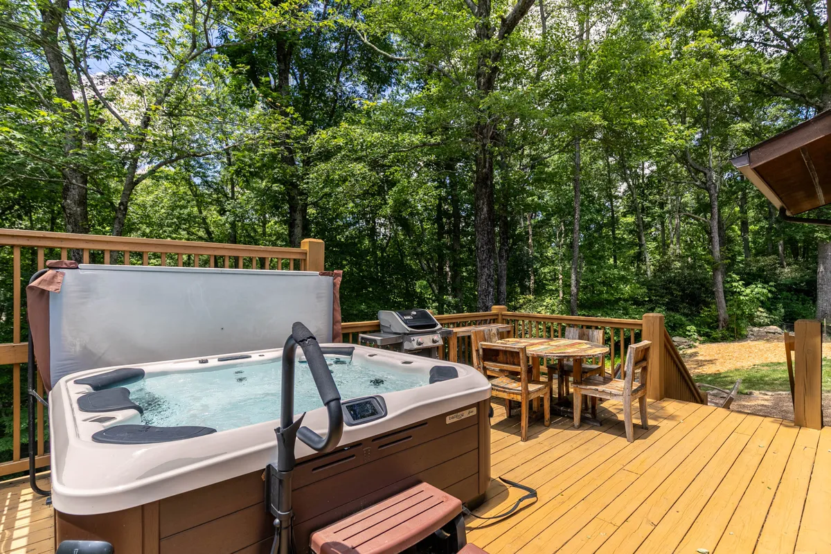 A tranquil wooden deck featuring a hot tub and a dining table, set against a natural backdrop. The space is ideal for quiet mornings, post-walk relaxation, or stargazing in the evenings, all while being close to the beauty of the surrounding landscape.