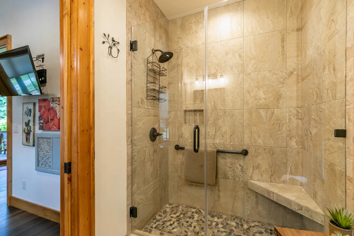 A modern bathroom with a glass shower enclosure, stone tile walls, and elegant fixtures creates a spa-inspired, serene environment. The design is clean and rejuvenating, ideal for self-care routines in a private suite.